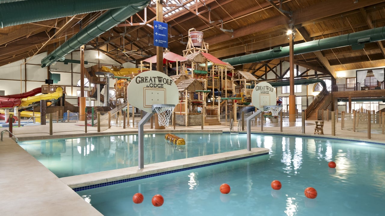 A large indoor water park featuring multiple slides and a basketball hoop for recreational activities