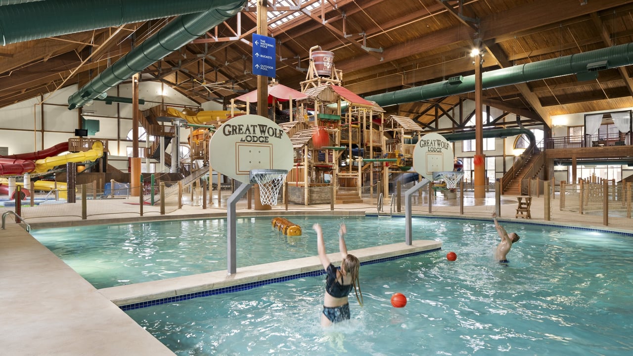 Family playing basketball in a large indoor water park