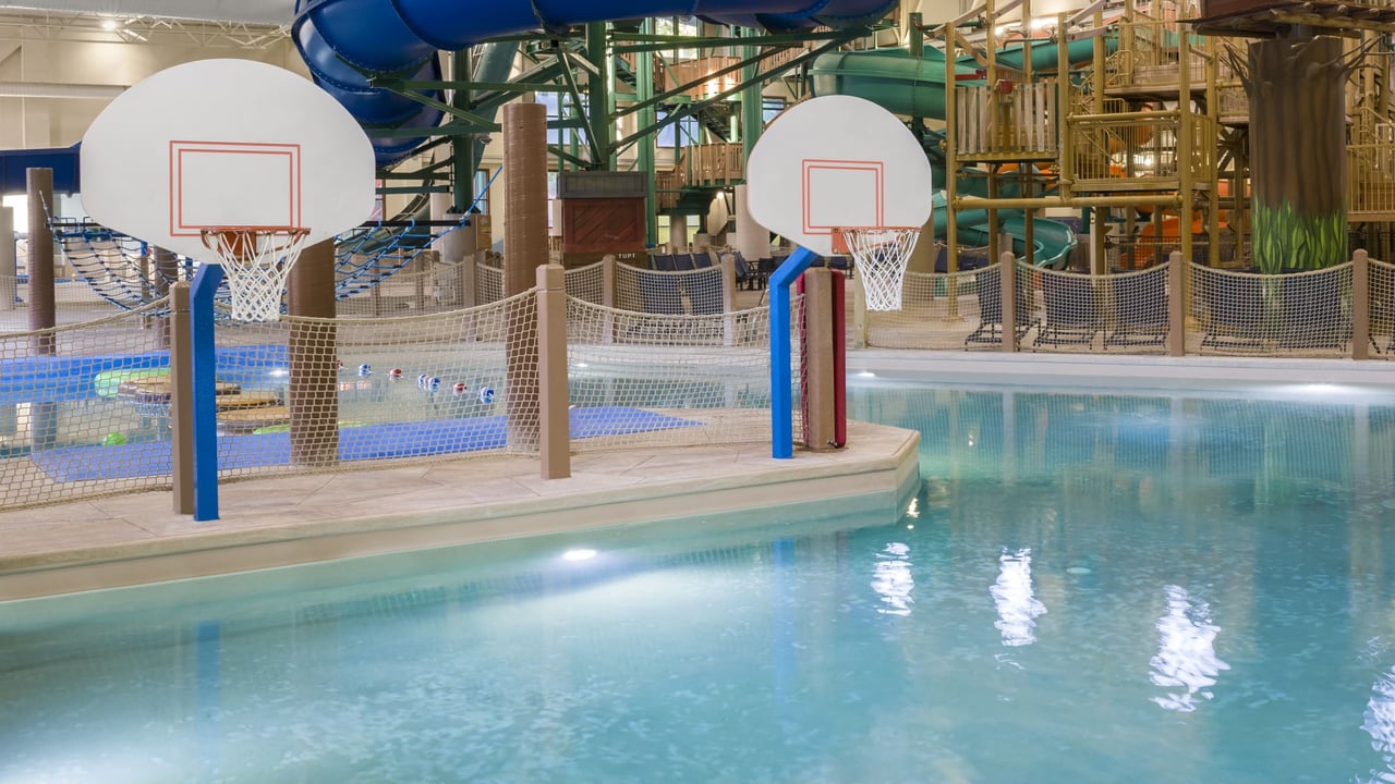 A vibrant water park featuring a basketball hoop and multiple water slides for fun and recreation.