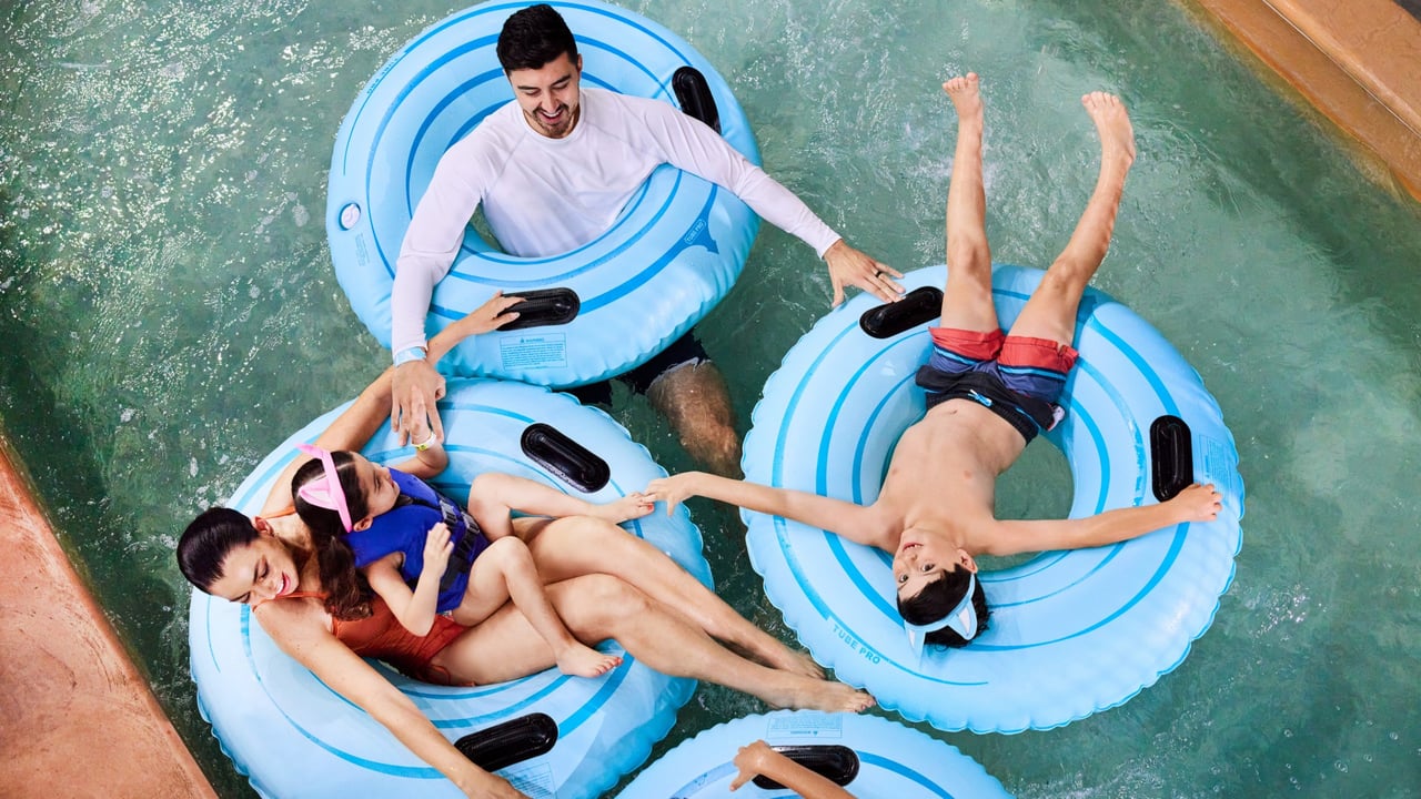 father pushes the tubes of family as they enjoy the lazy river water park attraction