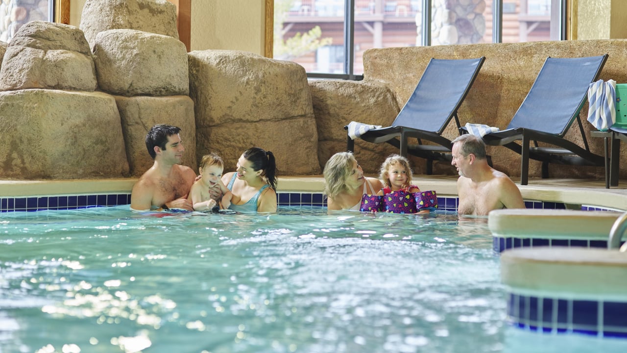 parents, grandparents and children relax in an indoor hot tub