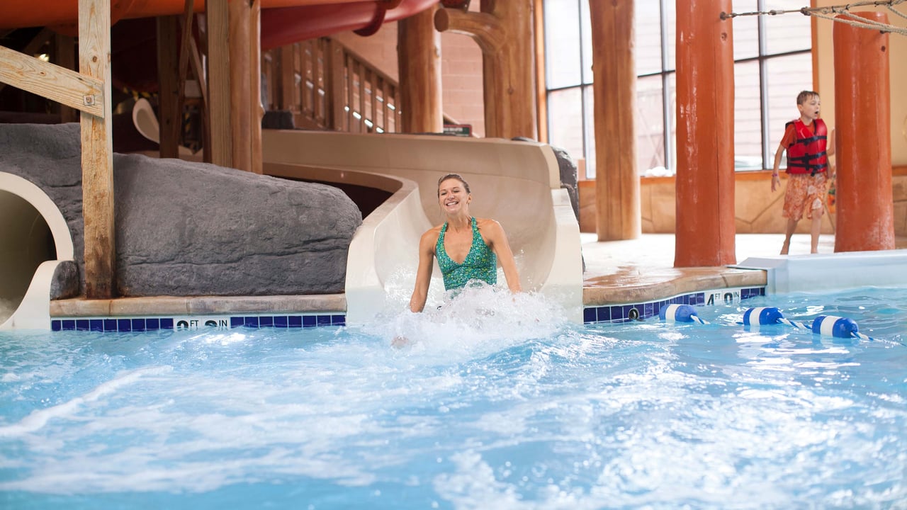 A woman riding down waterslide landing in splash pool