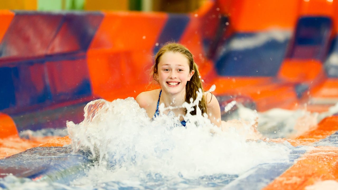 A young girl going down a red and blue waterslide