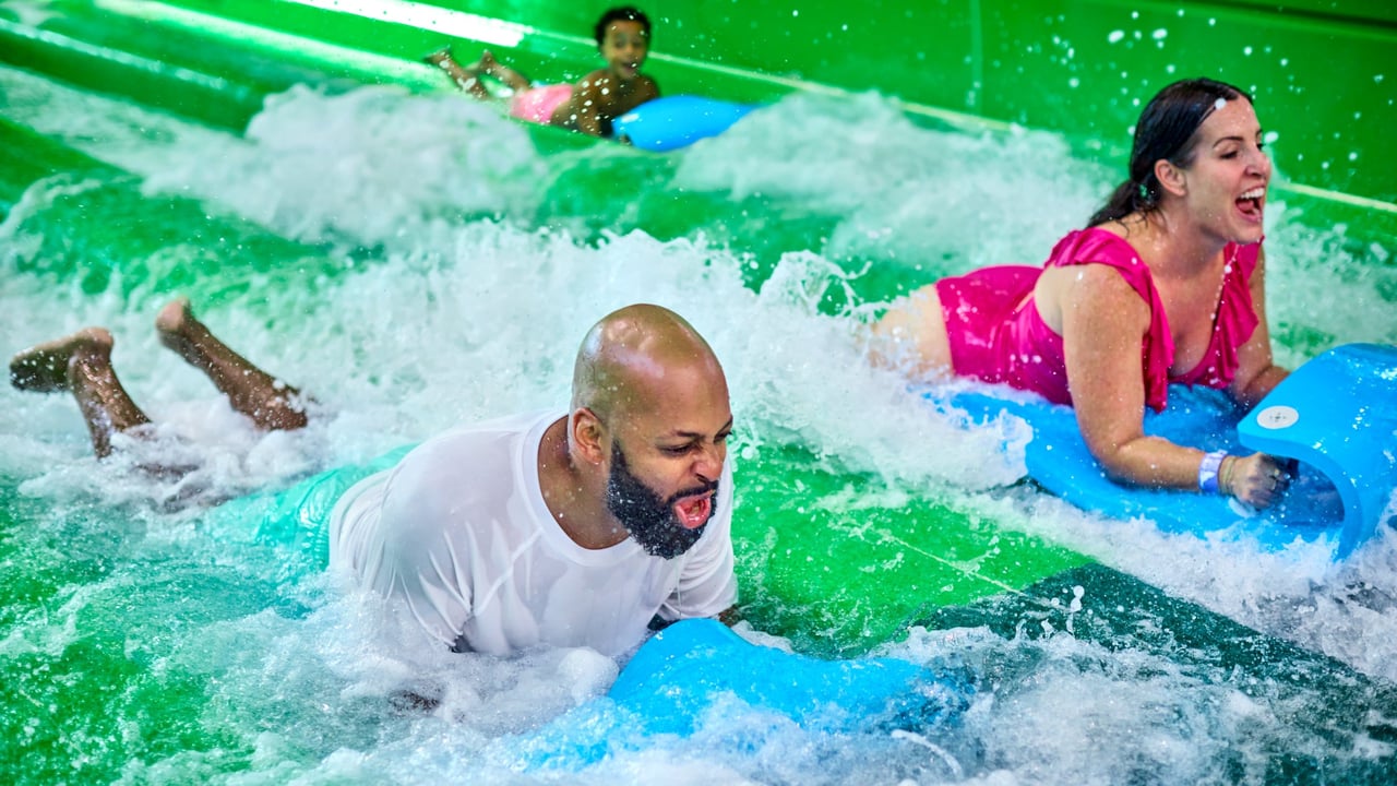 A couple going down a green waterslide