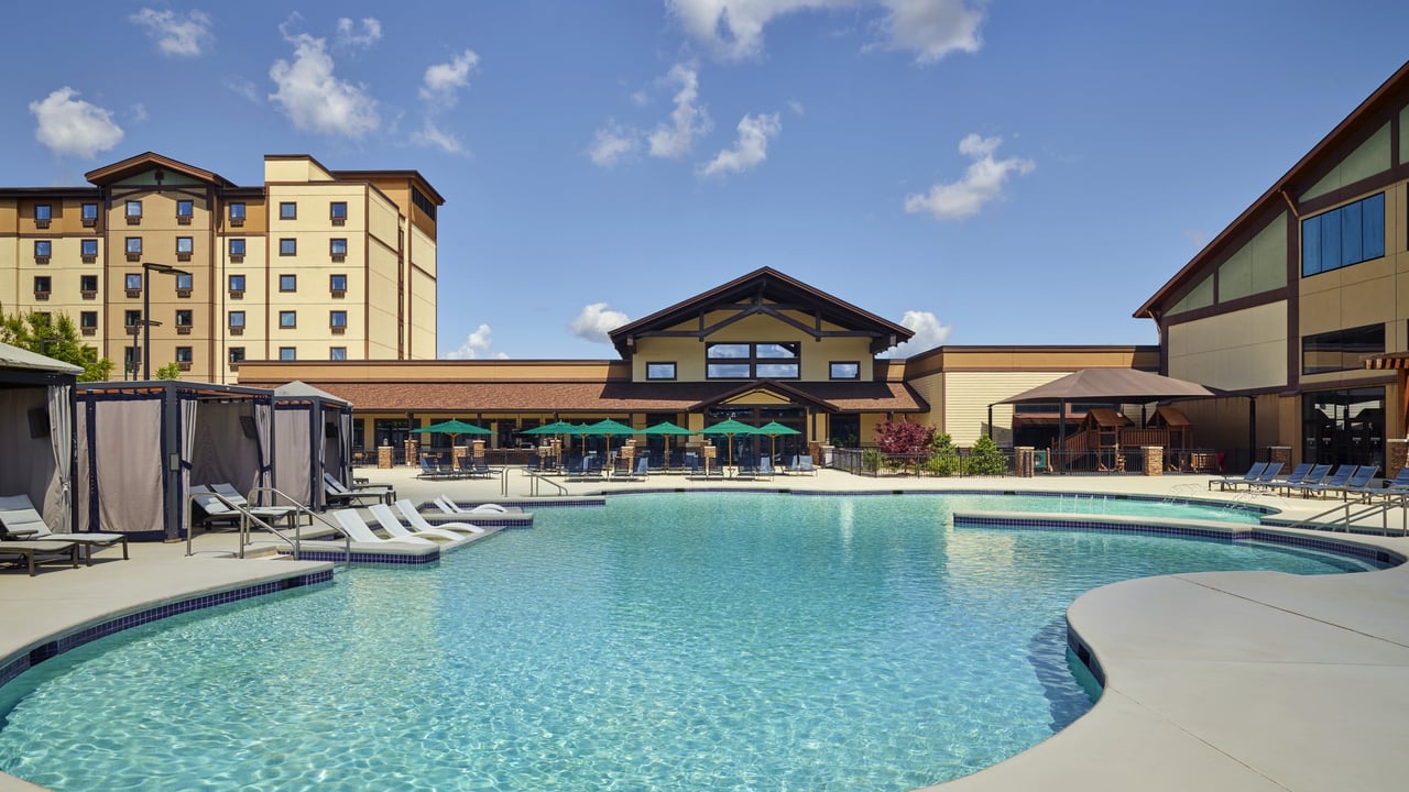 outdoor pool surrounded by cabanas and beach  chairs