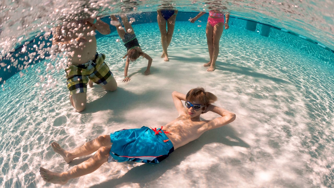 boy with goggles laying under water