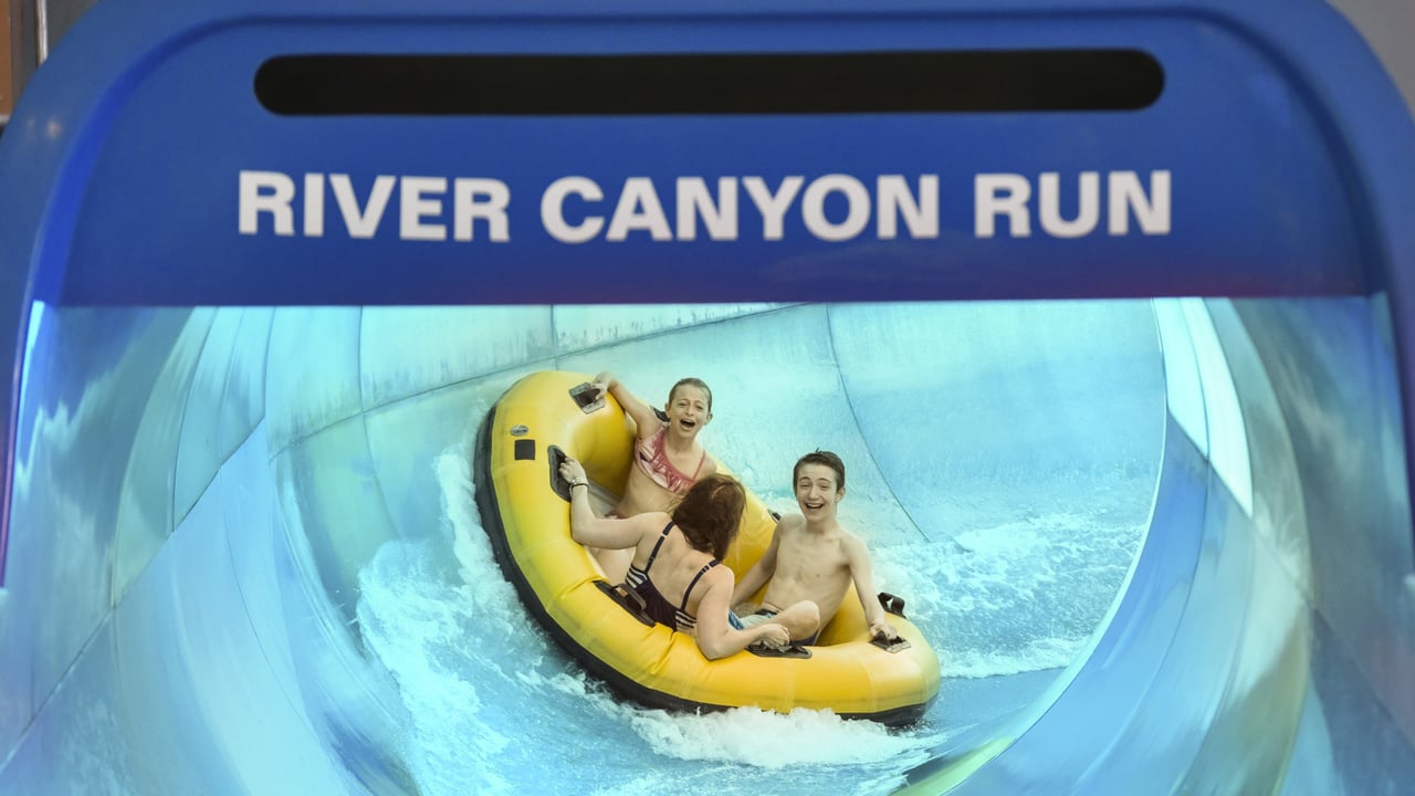 Family going down a blue water slide in a yellow raft