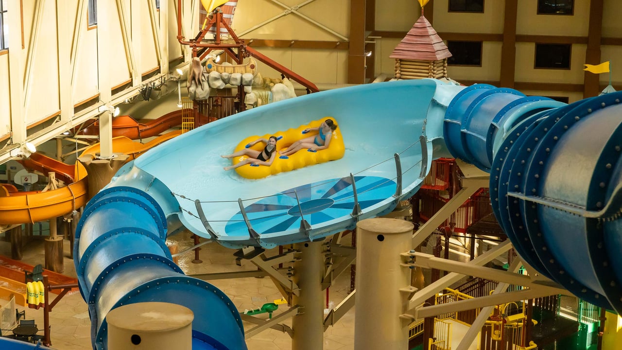 Two teenagers riding a yellow raft in an indoor water park