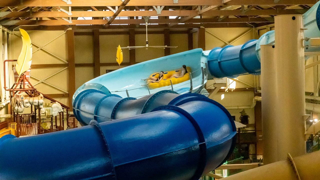 Two teenagers riding a yellow raft in an indoor water park
