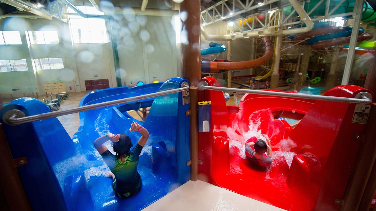 two kids about to go down a blue and a red water slides