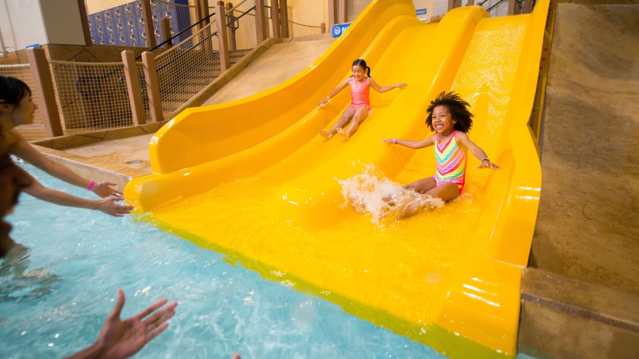 two little girls on yellow water slides