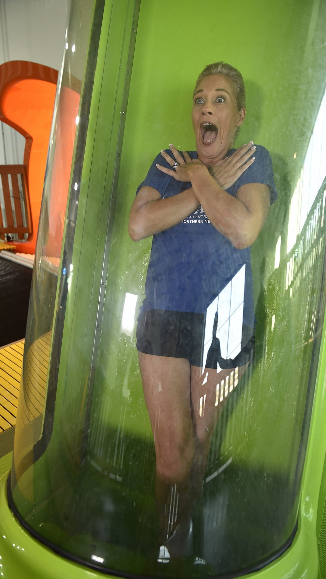 A woman stands in the chute of the Wolf Tail trapdoor waterslide with her arms crossed waiting to take the plunge.