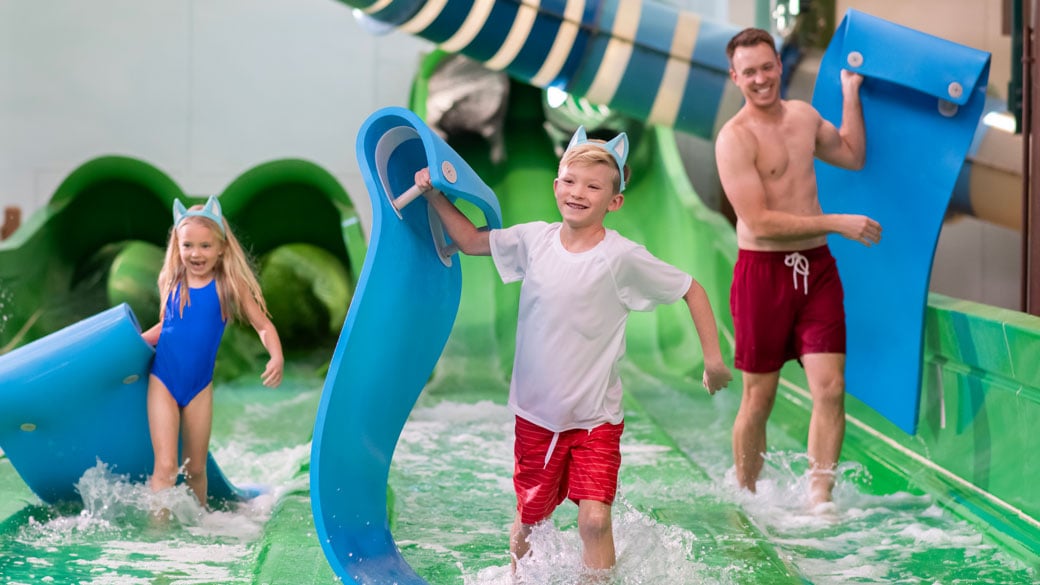 family holding rafts after coming down a water slide