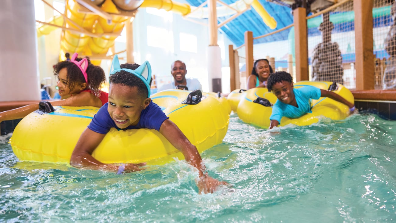 family floating in lazy river water ride using tubes