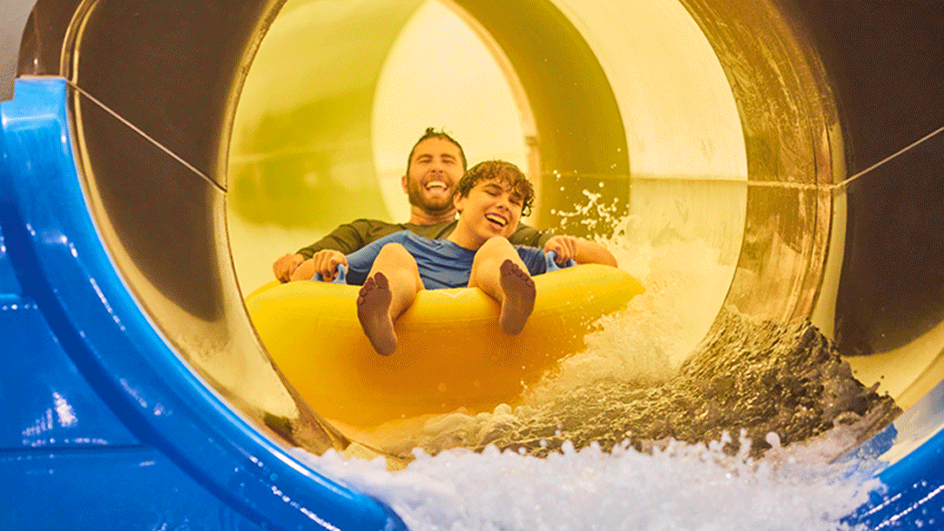 father and son coming down a water slide riding a tube