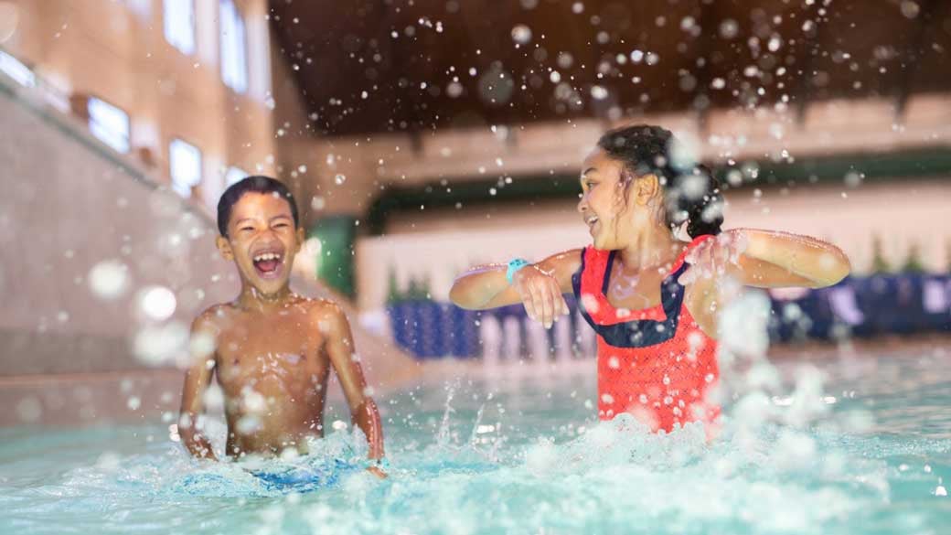 Brother and sister running in shallow pool