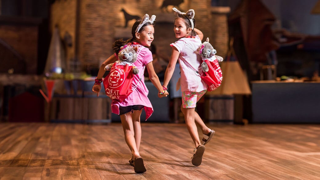 Two little girls running down the lobby of Great Wolf Lodge