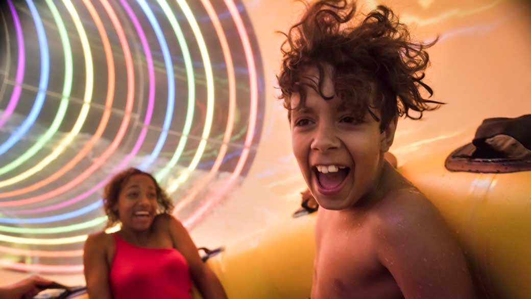 Young boy and mother sliding down a water slider