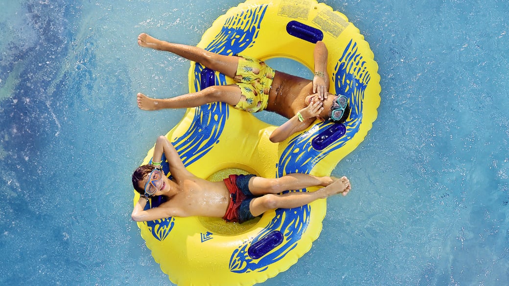 Two kids floating on a yellow float in a pool