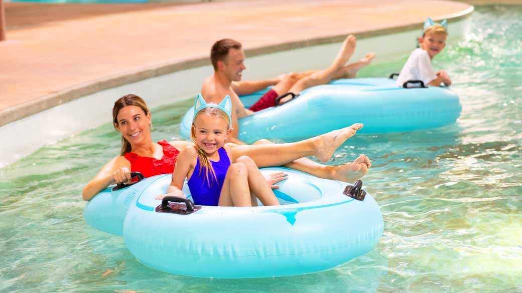family floating in lazy river water ride using tubes