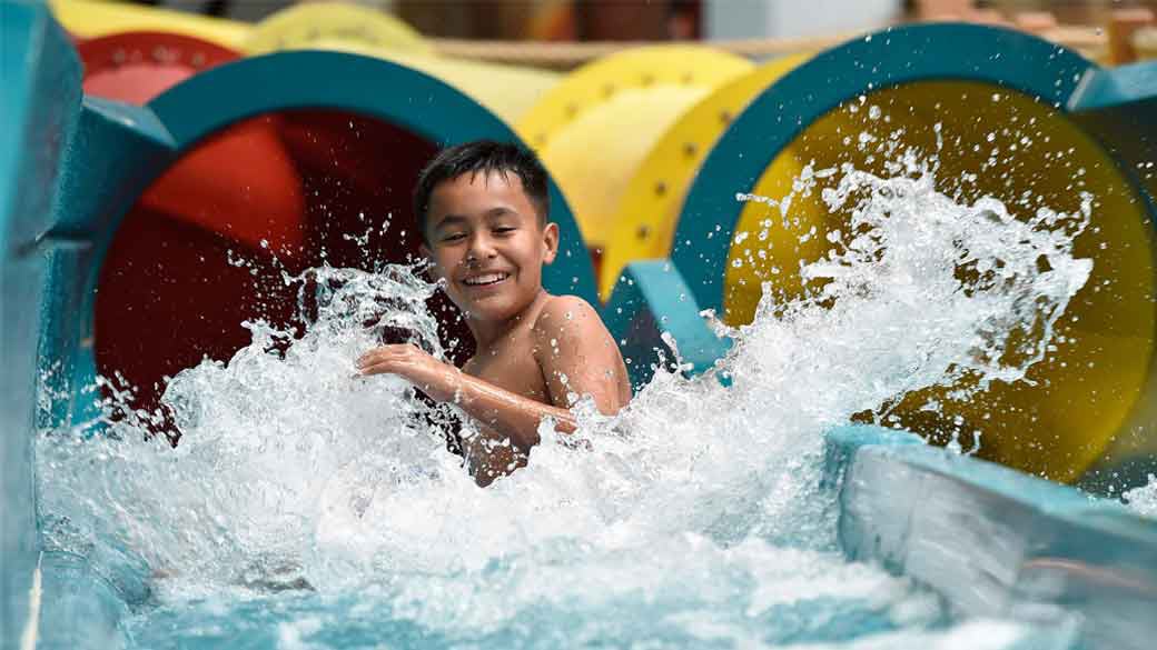 young boy sliding down on a water slide