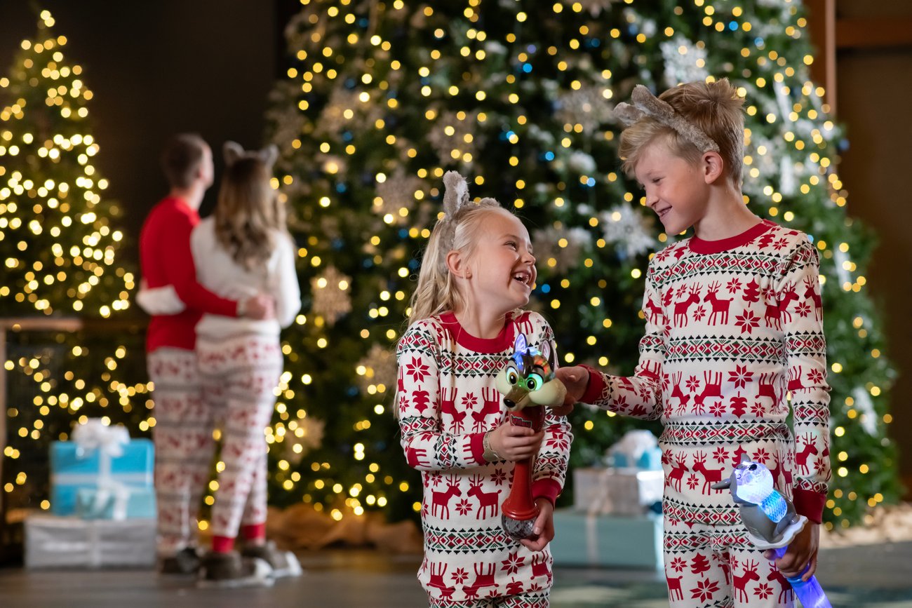 family standing in front of a christmas tree wearing holiday themed PJ's