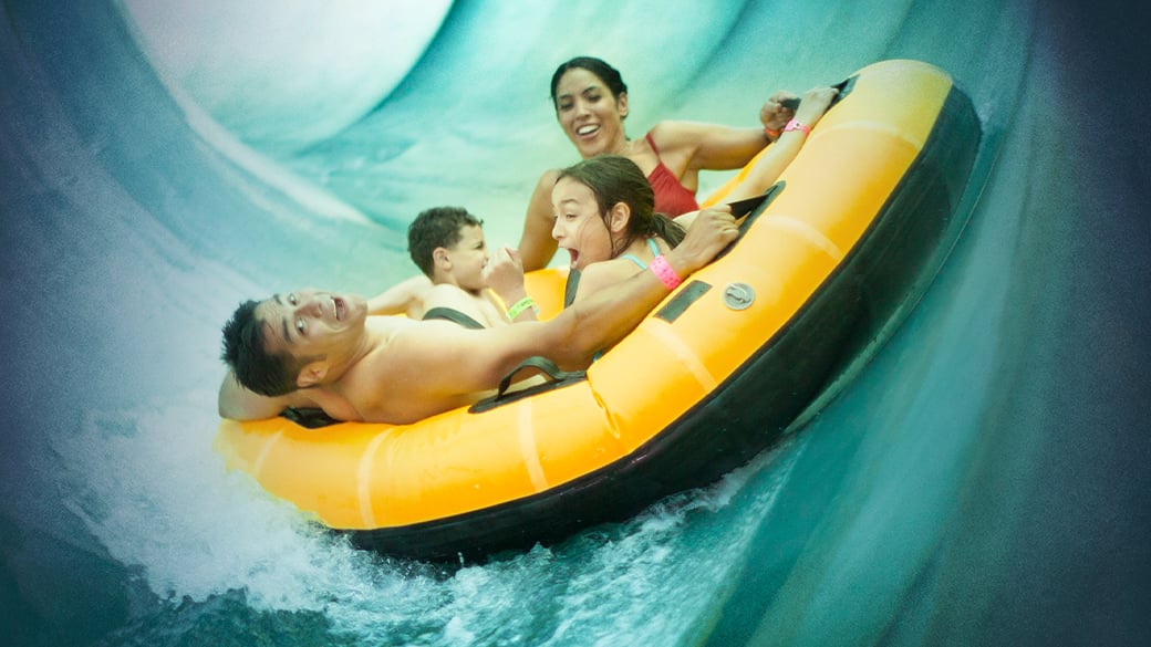 Family sliding down a water slider in a yellow floats