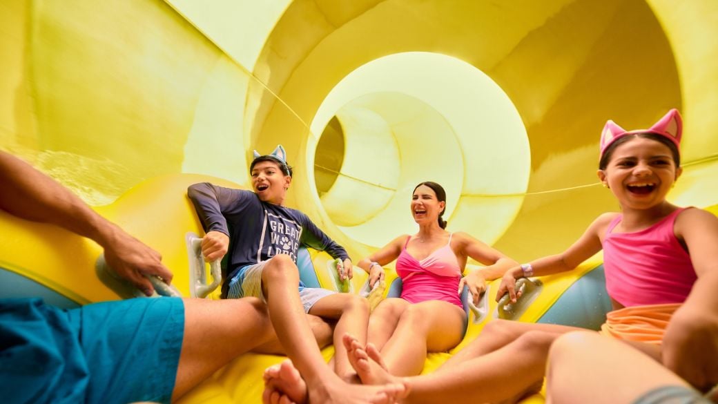 A family riding on a large tube going down a water slide