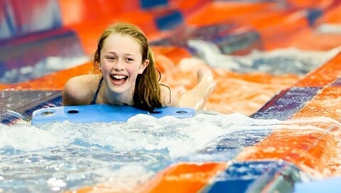 A girl smiles as she comes to the end of her slide