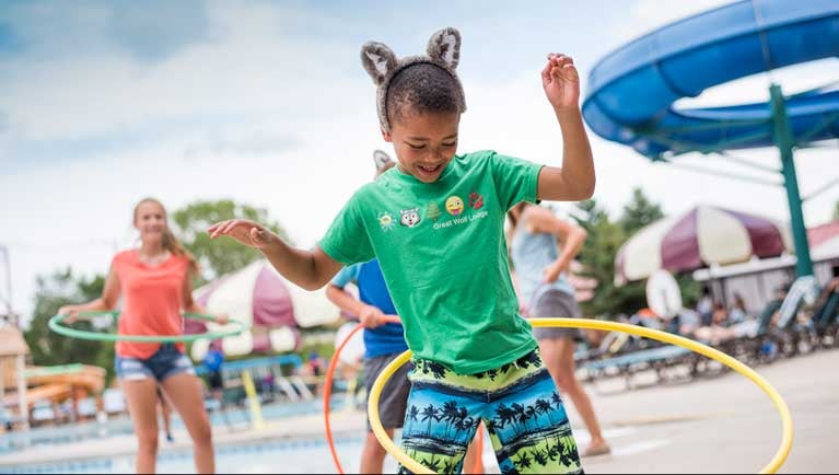 boy in green shirt and wolf ears hula hoops with kids behind him 