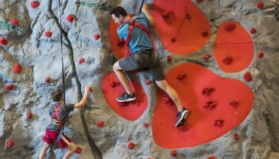 A family climbs a rock wall at Great Wolf Lodge indoor water park and resort.