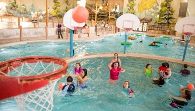 family playing basketball in indoor pool 