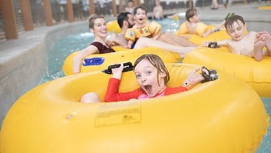 A girl float down the lazy river excitedly in her inner tube