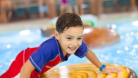 A boy balances himself on a float in the Frog Bog Log Walk pool at Great Wolf Lodge indoor water park and resort.