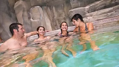 A family of four relaxes by the South Hot Springs pool at Great Wolf Lodge indoor water park and resort.