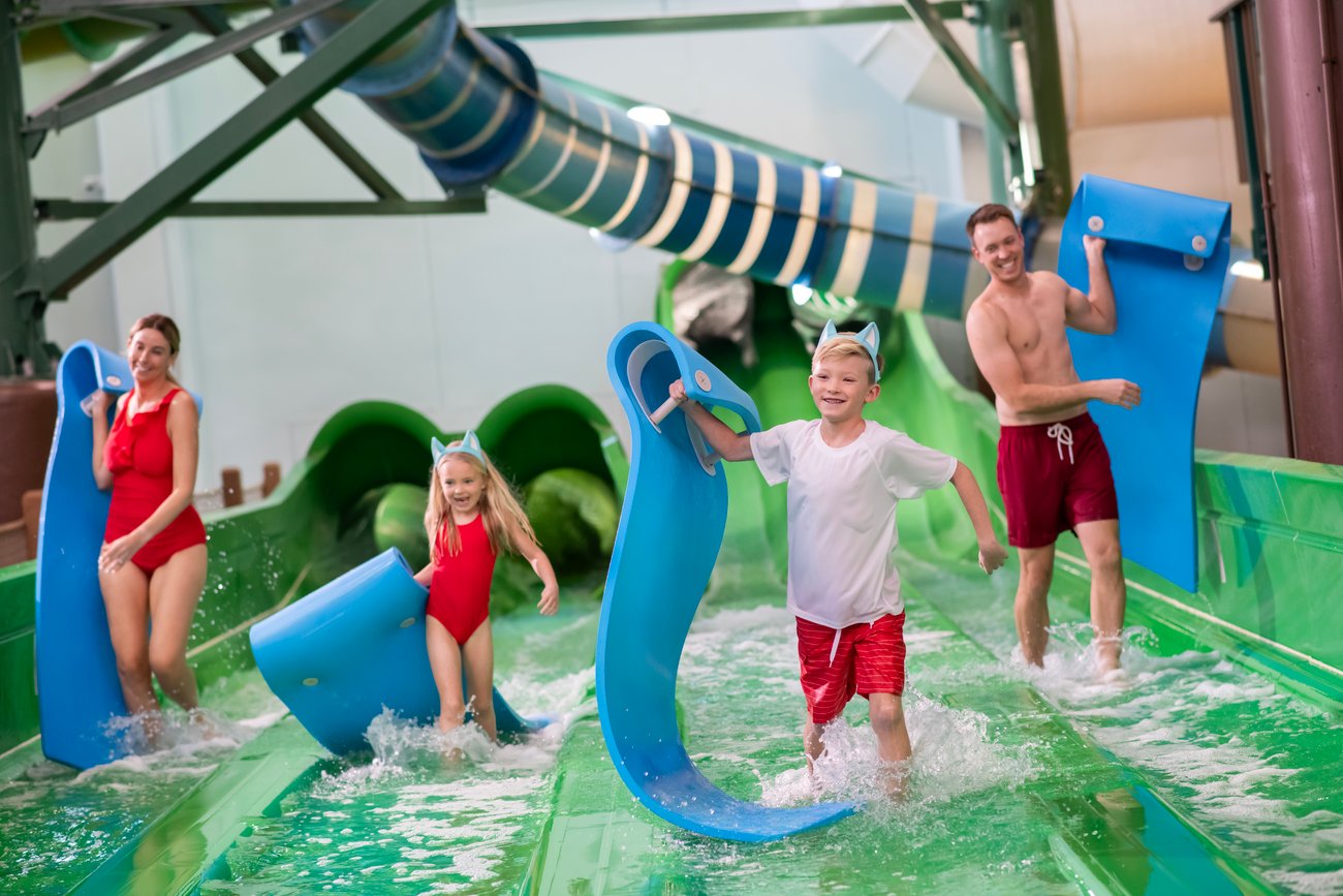 Family sliding down a water slide using mats