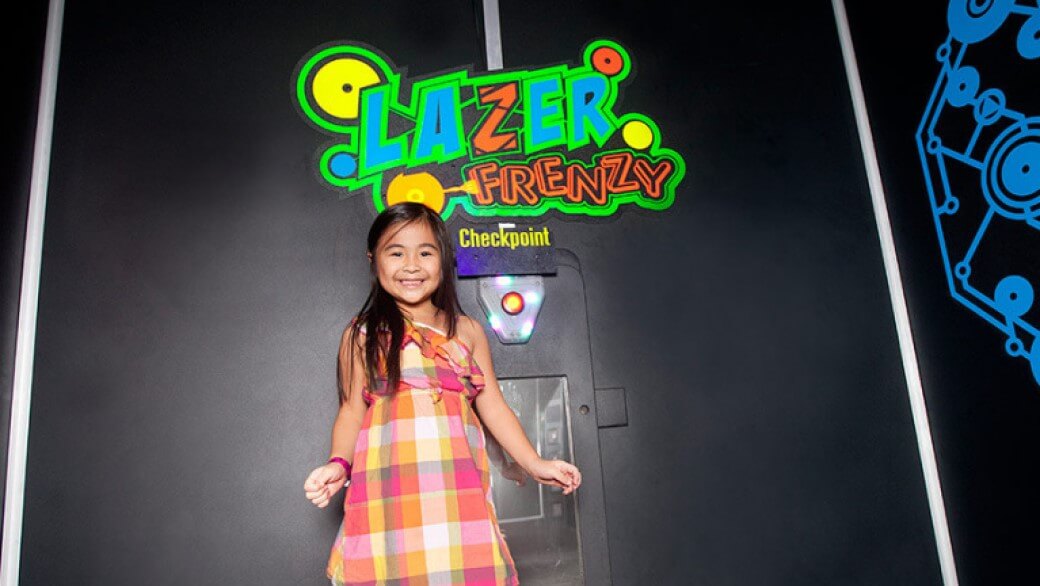 A girl smiles at the entrance of Lazer Frenzy at Great Wolf Lodge indoor water park and resort.