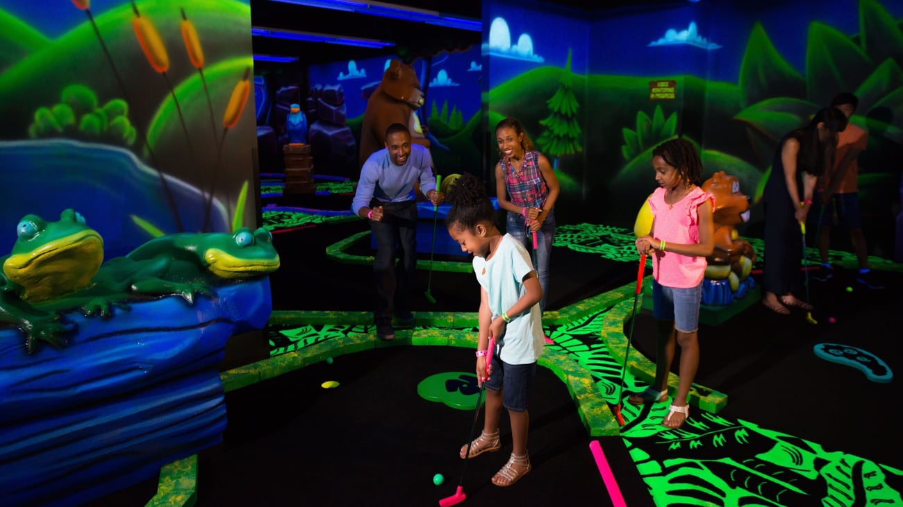 Family watching son play a hole of Glow Golf