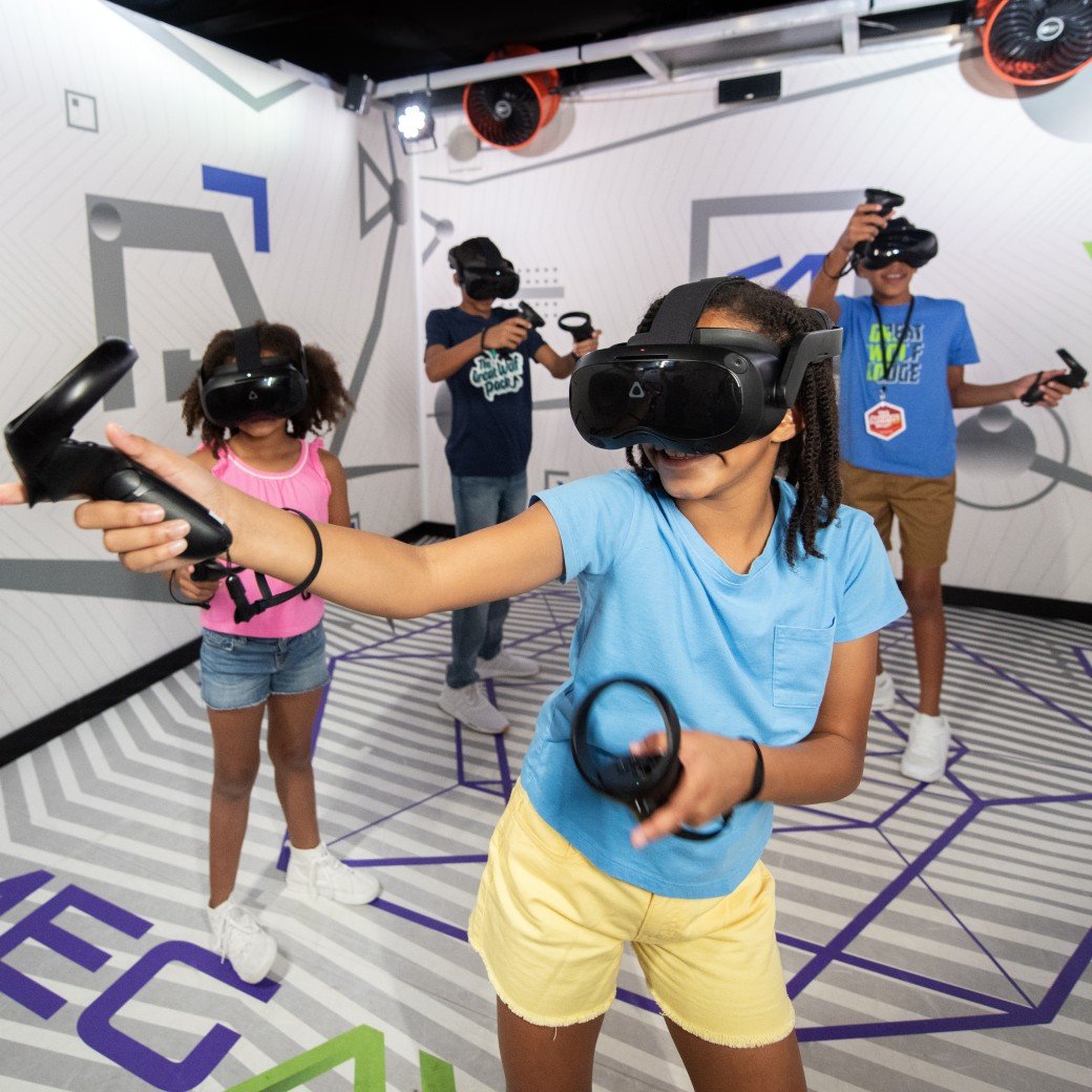 Kids wearing VR headsets play with controllers indoors