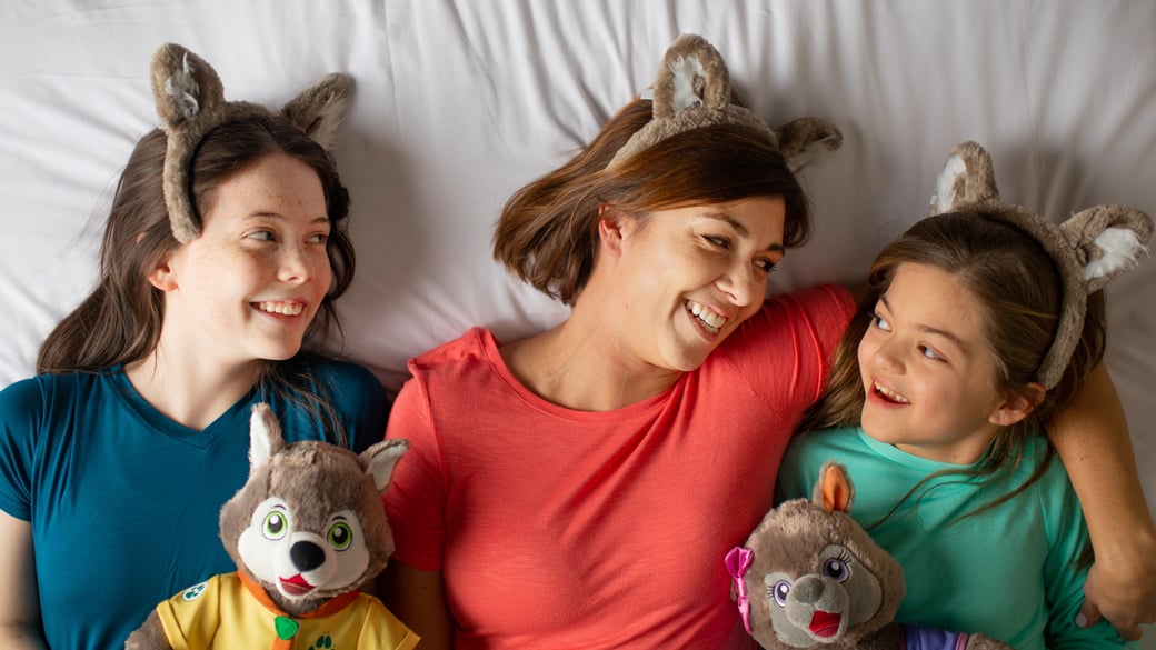 Mother laying down in bed with daughters.