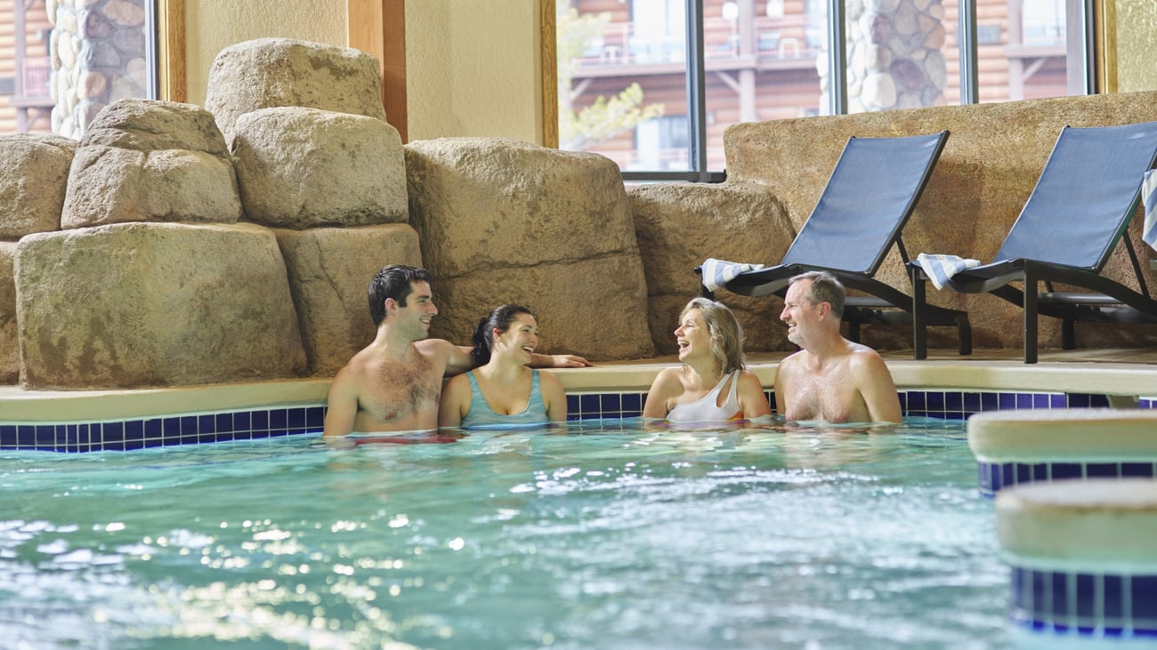 Two couples relax in an indoor hot tub
