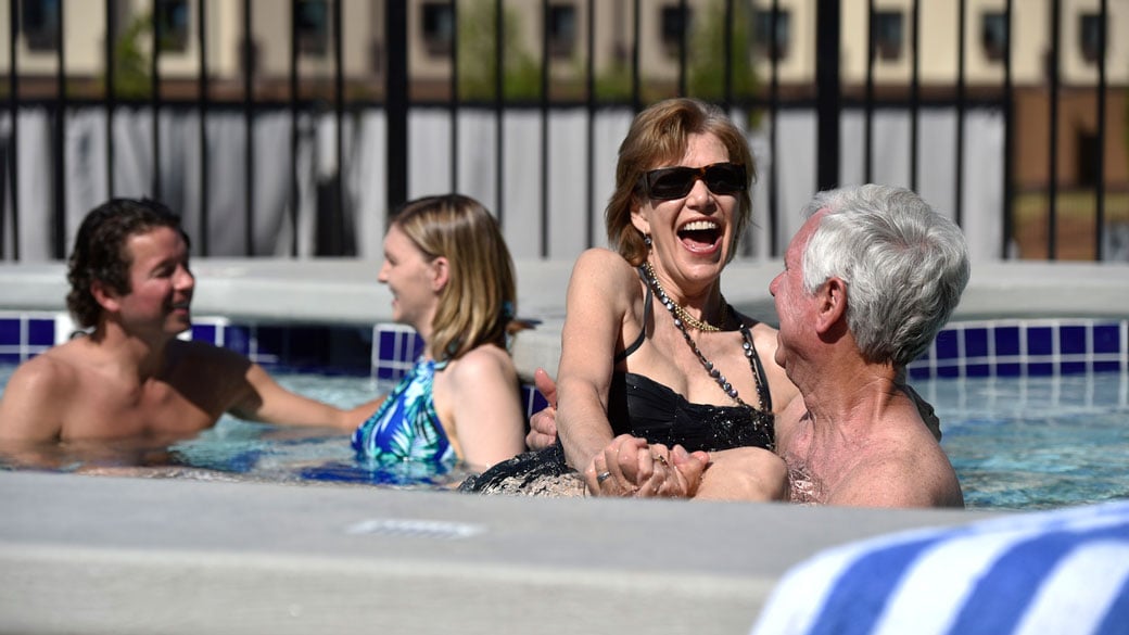 A couple relax in and on the side of the indoor pool 