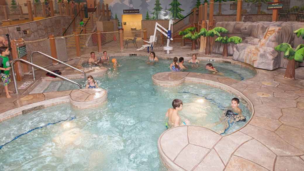 A couple relax in and on the side of the indoor pool 