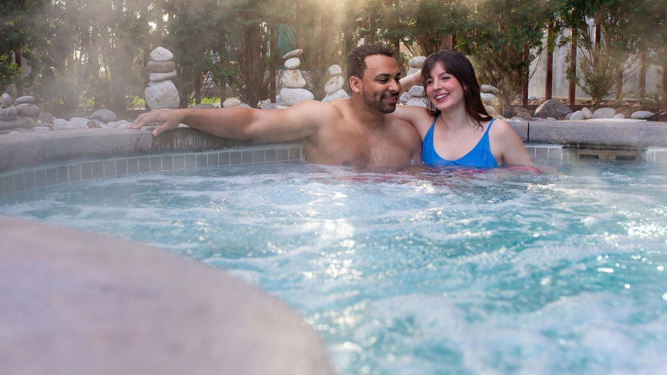 A couple relaxes in an outdoor hot tub