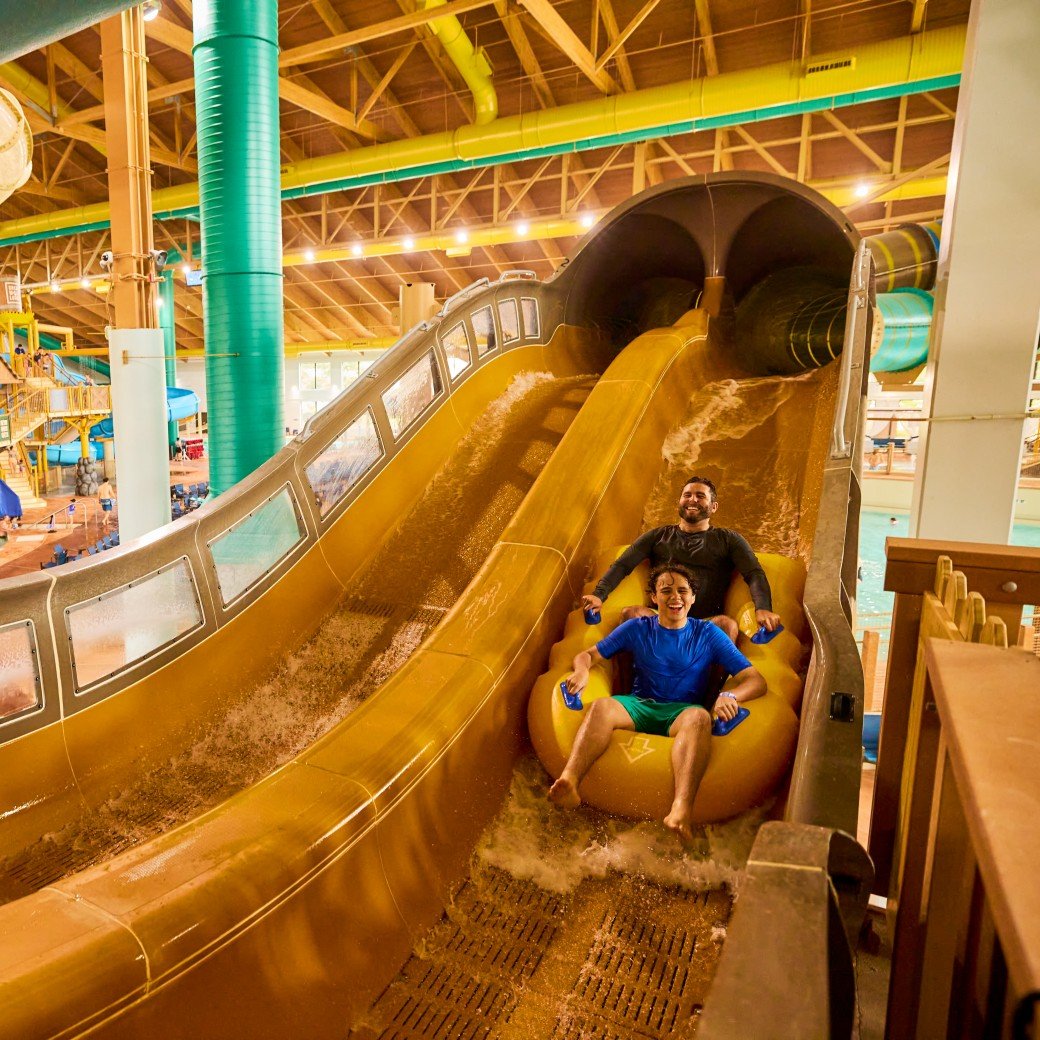 Boy rides down blue waterslide on yellow tube