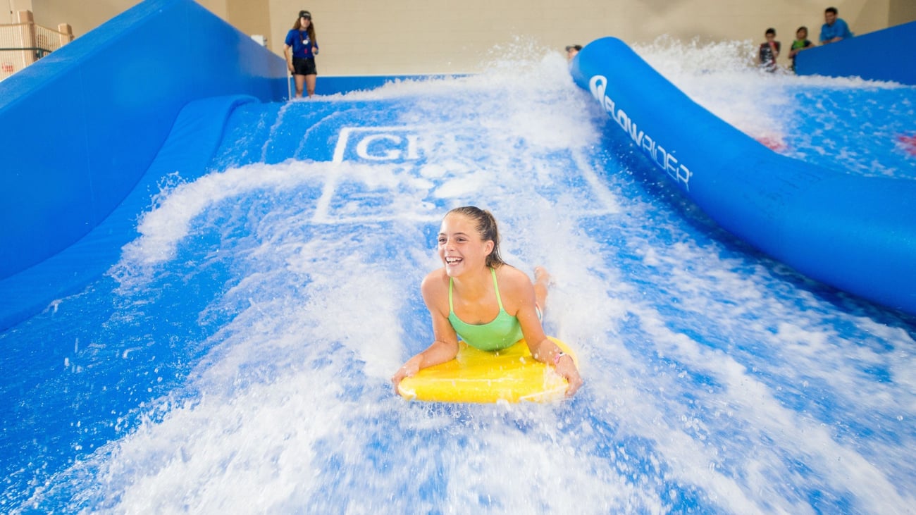 A child rides on a yellow boogie board in the water attraction