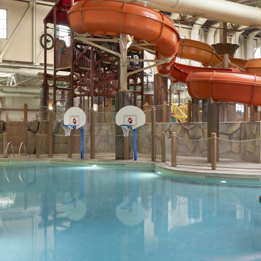 family playing basketball in indoor pool 