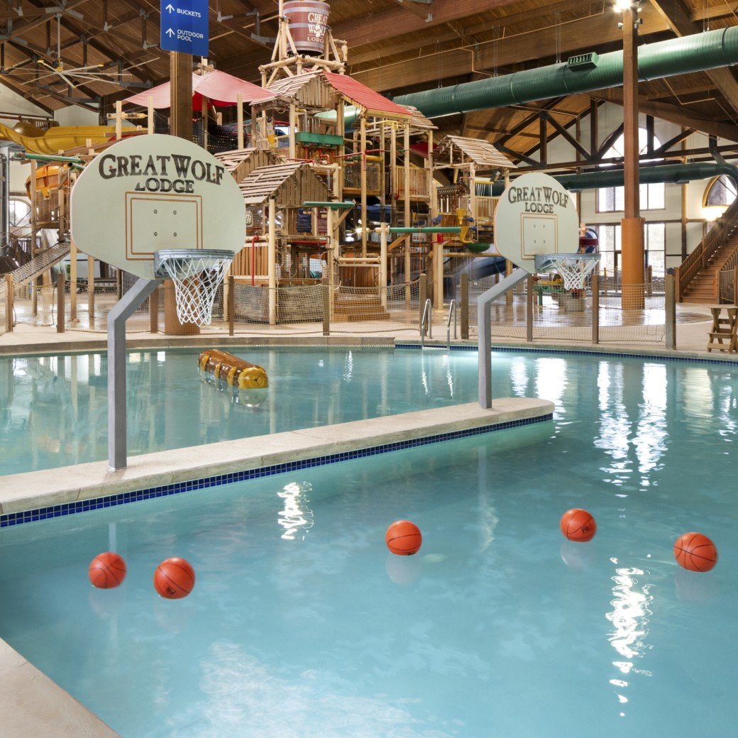 A large indoor water park featuring multiple slides and a basketball hoop for recreational activities.