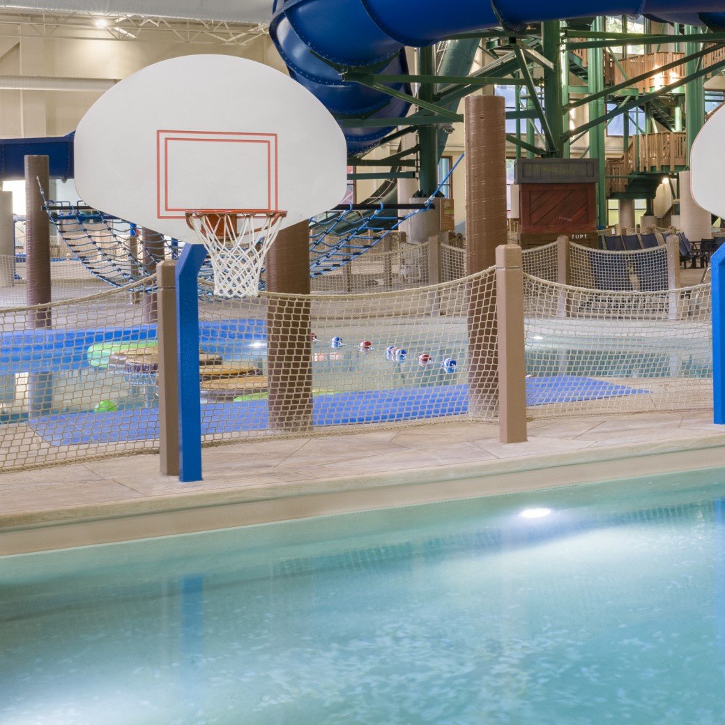 A vibrant water park featuring a basketball hoop and multiple water slides for fun and recreation.