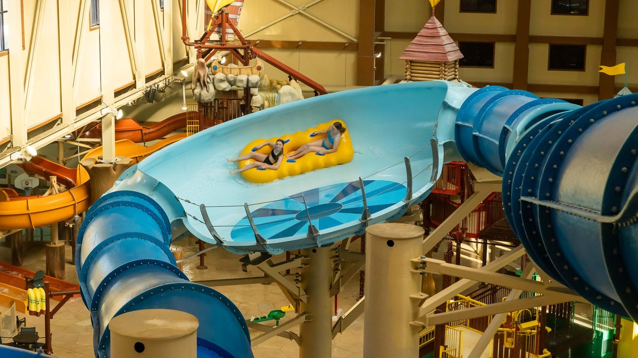Two teenagers riding a yellow raft in an indoor water park
